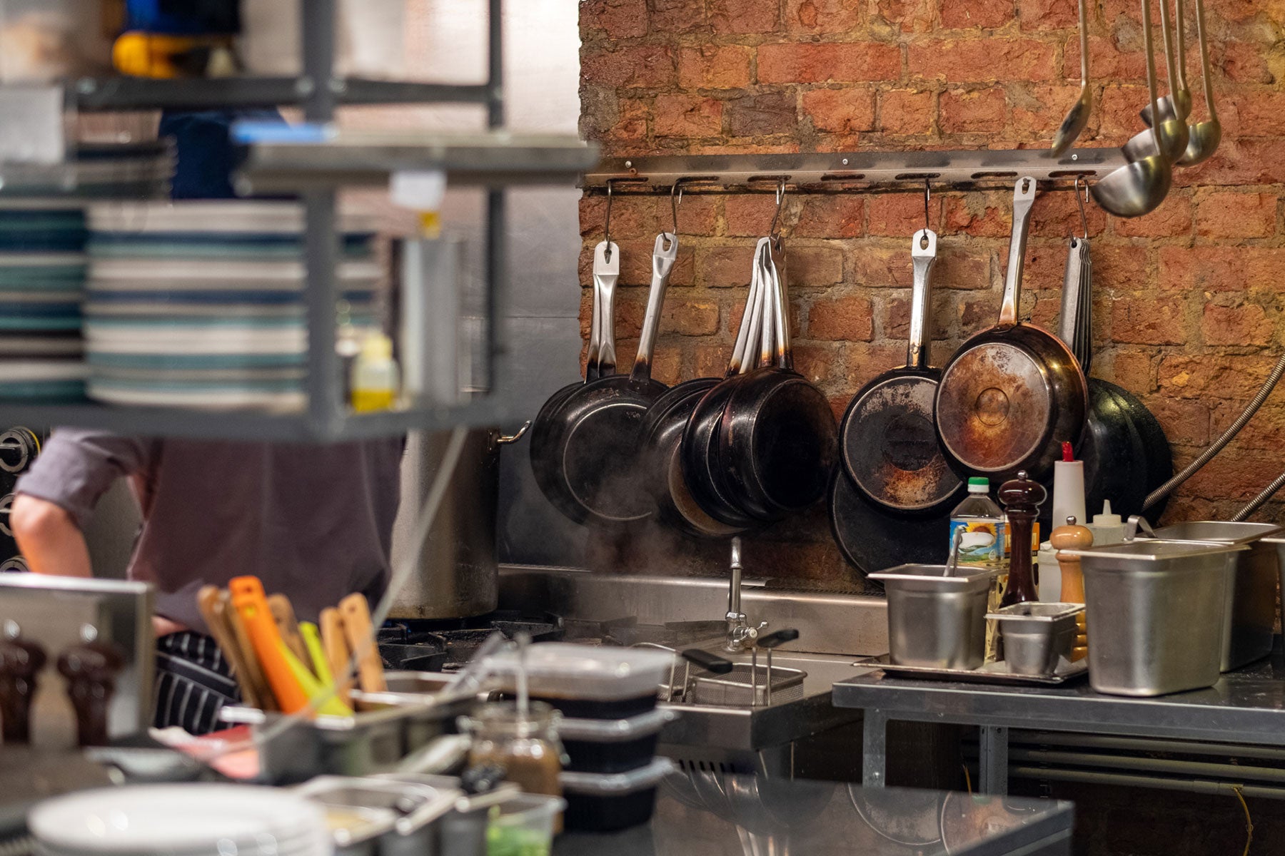 Cast iron pans hanging on a brick wall in a restaurant kitchen