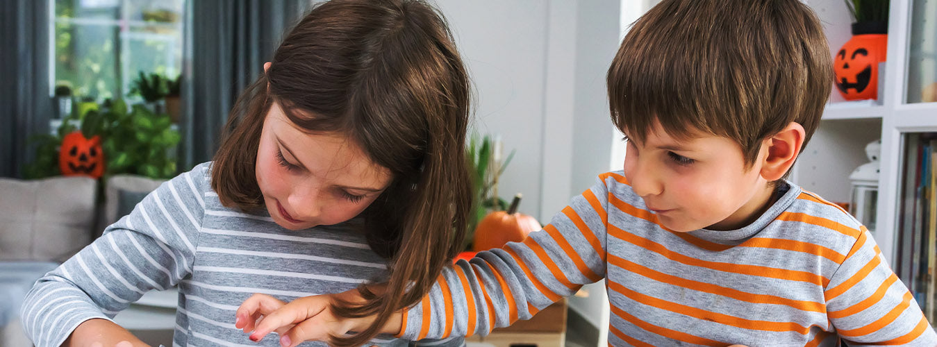 two kids make Halloween cookies and play with black icing 