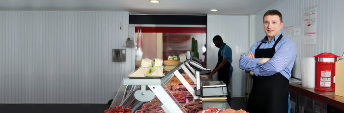 A person standing in front of a butcher counter with meat on display